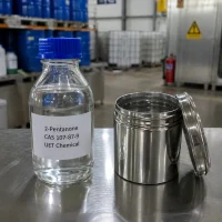 2-pentanone-mpk-liquid-sample-bottle-metal-can Clear glass bottle with blue cap containing liquid 2-Pentanone (MPK, CAS 107-87-9) placed next to an open stainless steel can on a metal lab table, UET Chemical brand sample display
