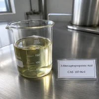 3-mercaptopropionic-acid-cas-107-96-0-pale-yellow-liquid-sample-beaker Pale yellow liquid sample of 3-Mercaptopropionic Acid CAS 107-96-0 in a transparent glass beaker on a metal lab bench, next to a label card showing product name and CAS number.