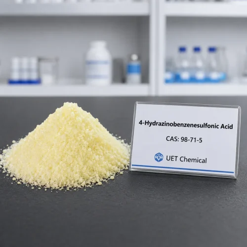 4-hydrazinobenzenesulfonic-acid-cas-98-71-5-yellow-powder-sample Pale yellow crystalline powder pile of 4-Hydrazinobenzenesulfonic Acid CAS 98-71-5 on a dark lab bench, next to a clear label card showing UET Chemical branding.