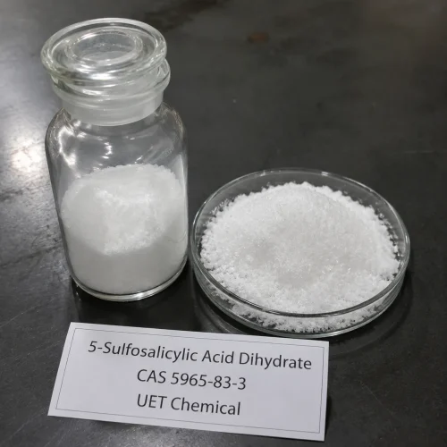 5-sulfosalicylic-acid-dihydrate-powder-sample-glass-bottle White crystalline powder of 5-Sulfosalicylic Acid Dihydrate (CAS 5965-83-3) displayed in clear glass reagent bottle and glass petri dish on dark lab surface, UET Chemical brand sample for purity verification