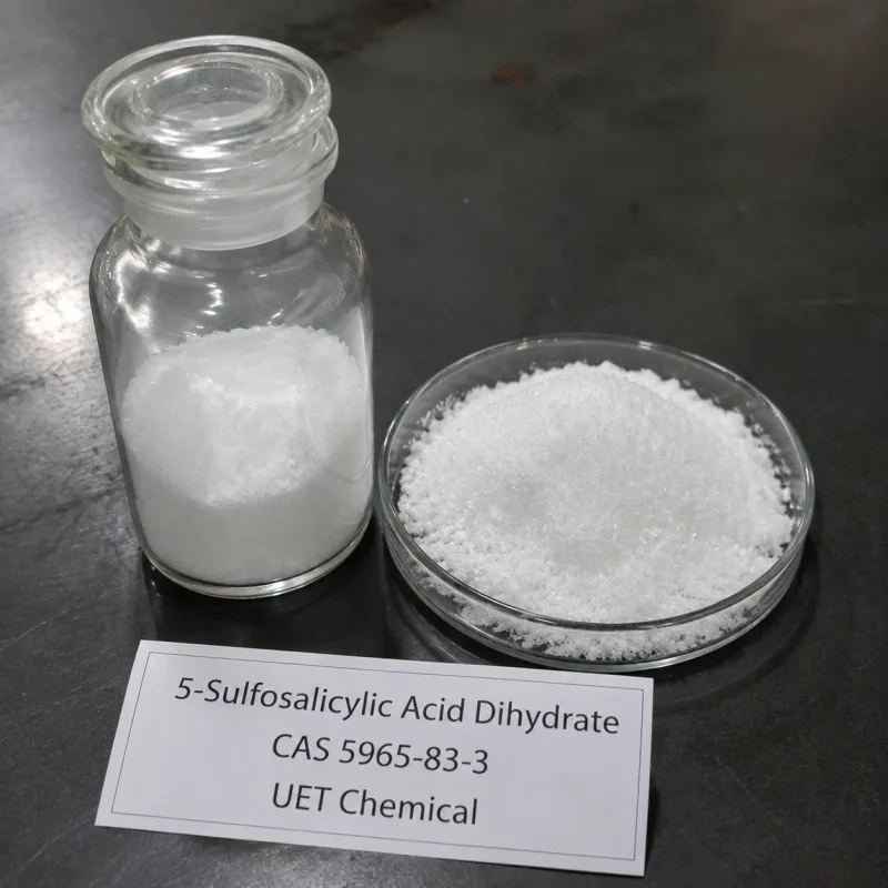 5-sulfosalicylic-acid-dihydrate-powder-sample-glass-bottle White crystalline powder of 5-Sulfosalicylic Acid Dihydrate (CAS 5965-83-3) displayed in clear glass reagent bottle and glass petri dish on dark lab surface, UET Chemical brand sample for purity verification