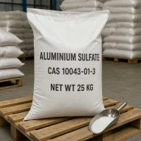 aluminium-sulfate-cas-10043-01-3-white-crystalline-granules-packaging Close-up view of Aluminium Sulfate (CAS 10043-01-3) white crystalline granules displayed with a stainless steel scoop next to a 25kg woven bag, showcasing the fine physical texture of this premium water treatment flocculant.