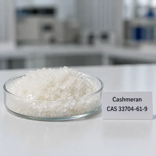 White crystalline cashmeran fragrance ingredient CAS 33704-61-9, woody musk aroma chemical, in glass dish with label card