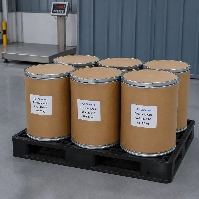 d-tartaric-acid-25kg-cardboard-drum-factory-floor Six cardboard drums (Net 25 kg each) of D-Tartaric Acid (CAS 147-71-7) on black plastic pallet in factory setting, labeled UET Chemical, industrial-grade packaging for chemical synthesis and flavoring agent supply