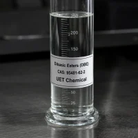 dibasic-esters-dbe-cas-95481-62-2-clear-liquid-sample Clear liquid sample of Dibasic Esters (DBE) CAS 95481-62-2 in a transparent glass graduated cylinder on a dark lab bench, label showing UET Chemical branding.