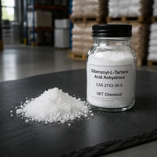 dibenzoyl-l-tartaric-acid-anhydrous-white-powder-sample Close-up of white crystalline powder of Dibenzoyl-L-Tartaric Acid Anhydrous (CAS 2743-38-6) in a glass sample bottle and on a black slate surface, UET Chemical