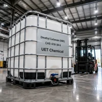 dimethyl-carbonate-dmc-cas-616-38-6-1000kg-white-ibc-tote-tank White IBC tote tank of Dimethyl Carbonate (DMC) CAS 616-38-6 on black pallet in warehouse, label showing UET Chemical branding and forklift in background.