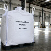 diphenyl-bismuth-chromate-cas-102-06-7-white-ton-bag-fibc Large white FIBC ton bag of Diphenyl Bismuth Chromate CAS 102-06-7 with label showing UET Chemical branding, placed on a black plastic pallet inside a spacious industrial warehouse.