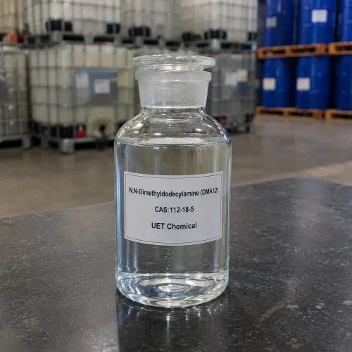 dma12-clear-liquid-sample-glass-reagent-bottle-u-et-chemical Clear glass reagent bottle filled with colorless liquid N,N-Dimethyldodecylamine (DMA12, CAS 112-18-5) on dark table surface, labeled UET Chemical, high purity sample for laboratory testing and quality inspection