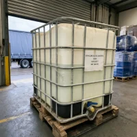 egda-cas-111-55-7-1000kg-ibc-tote-bulk-packaging 1000kg IBC bulk container of EGDA (Ethylene Glycol Diacetate) CAS 111-55-7 placed on a pallet in a warehouse, featuring a blue bottom discharge valve for efficient industrial liquid transfer.