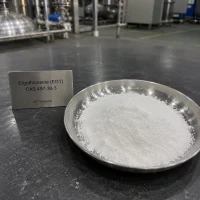 Close-up view of white crystalline Ergothioneine (EGT) CAS 497-30-3 powder in a metal dish with stainless steel reactors in background, high purity anti-aging cosmetic ingredient sample from UET Chemical manufacturer.