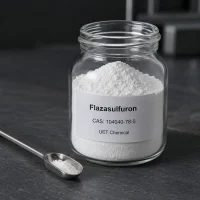 flazasulfuron-cas-104040-78-0-white-powder-sample-glass-jar Fine white powder sample of Flazasulfuron CAS 104040-78-0 in a clear glass jar with a stainless steel scoop beside it on a dark stone surface, label showing UET Chemical branding and product details.