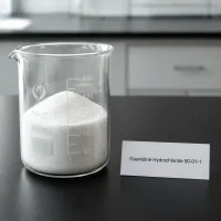 guanidine-hydrochloride-cas-50-01-1-white-crystalline-powder-sample White crystalline powder sample of Guanidine Hydrochloride CAS 50-01-1 in a glass beaker on a lab bench, with product label showing chemical name and CAS number.