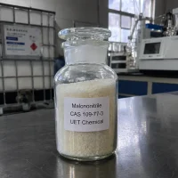 malononitrile-cas-109-77-3-glass-sample-bottle-crystalline-solid Glass reagent bottle with ground glass stopper containing white crystalline solid Malononitrile (CAS 109-77-3) on stainless steel lab bench, labeled UET Chemical, IBC tank visible in background