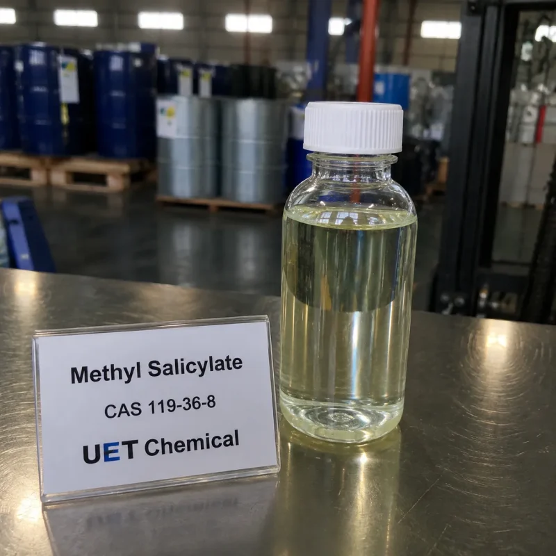 methyl-salicylate-cas-119-36-8-liquid-sample-bottle-u-et-chemical Clear plastic sample bottle containing pale yellow liquid Methyl Salicylate (CAS 119-36-8) next to a display card on stainless steel surface, labeled UET Chemical, sample for flavor, fragrance or pharmaceutical grade raw material