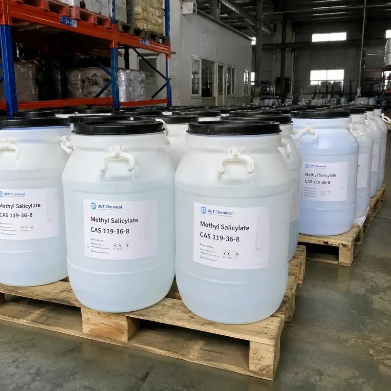 methyl-salicylate-cas-119-36-8-white-plastic-drum-pallet-warehouse Multiple white plastic drums of liquid Methyl Salicylate (CAS 119-36-8) neatly arranged on wooden pallets in warehouse storage, labeled UET Chemical, bulk packaging for industrial solvent and pharmaceutical applications