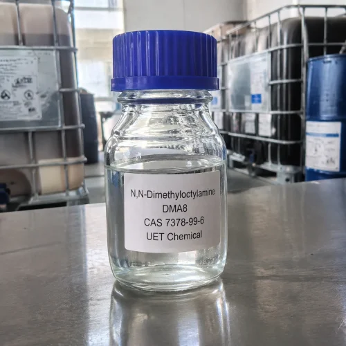 n-n-dimethyloctylamine-dma8-cas-7378-99-6-glass-sample-bottle Small clear glass bottle with blue cap containing colorless liquid N,N-Dimethyloctylamine (DMA8, CAS 7378-99-6) on stainless steel lab bench, labeled UET Chemical, IBC drums in background, sample for quality inspection