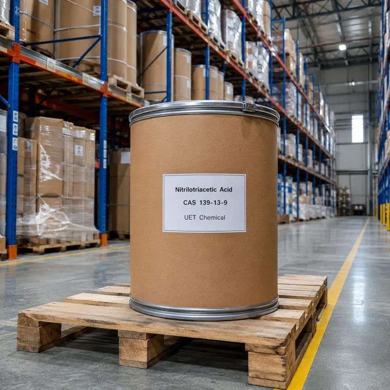 nitrilotriacetic-acid-nta-cas-139-13-9-fiber-drum-warehouse-uetchmical Fiber drum of Nitrilotriacetic Acid (NTA) CAS 139-13-9 on a wooden pallet in a warehouse aisle, showcasing industrial-grade packaging and stock availability by UET Chemical.