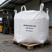 nitrilotriacetic-acid-nta-cas-139-13-9-ton-bag-bulk-supply-uetchmical Large white ton bag of Nitrilotriacetic Acid (NTA) CAS 139-13-9 on a wooden pallet near a forklift, indicating bulk industrial supply and logistics capability by UET Chemical.