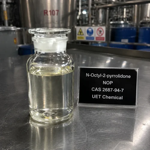 nop-n-octyl-2-pyrrolidone-sample-bottle-lab Clear glass reagent bottle filled with colorless liquid N-Octyl-2-pyrrolidone (NOP, CAS 2687-94-7) on stainless steel lab bench beside black identification sign, labeled UET Chemical, sample for solvent performance testing