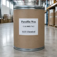 paraffin-wax-bulk-drum-warehouse-cas-8002-74-2 Industrial paraffin wax in cardboard drum with metal lid, labeled CAS 8002-74-2 and UET Chemical, stored in warehouse for bulk export