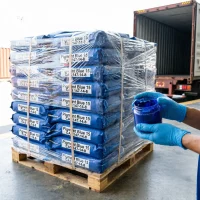 phthalocyanine-blue-pigment-blue-15-pallet-export-container Export shipment of Phthalocyanine Blue (Pigment Blue 15) 25kg paper bags stacked on a wooden pallet and shrink-wrapped, with gloved hands presenting an example pigment paste sample in front of a logistics container.