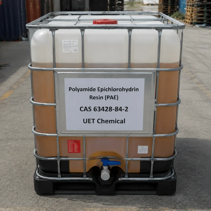 polyamide-epichlorohydrin-resin-pae-cas-63428-84-2-ibc-tote-tank An IBC tote tank containing Polyamide Epichlorohydrin Resin (PAE) CAS 63428-84-2 with amber liquid visible inside, featuring a metal cage and discharge valve, located in an outdoor storage yard.
