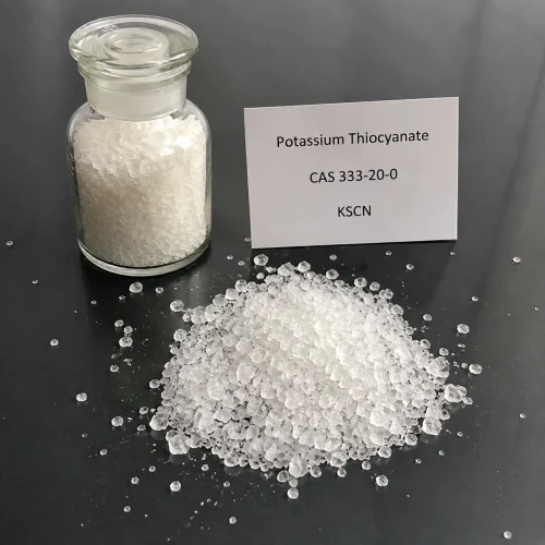White crystalline Potassium Thiocyanate (KSCN, CAS 333-20-0) in clear glass reagent bottle with scattered crystals on black surface, labeled UET Chemical, sample for analytical or industrial use verification