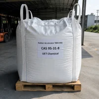rubber-accelerator-tbbs-ns-cas-95-31-8-1000kg-ton-bag A large white ton bag of Rubber Accelerator TBBS (NS) CAS 95-31-8 on a wooden pallet in a warehouse, with a forklift visible in the background.