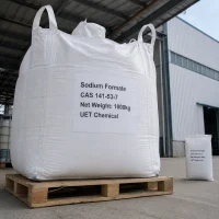 sodium-formate-cas-141-53-7-1000kg-ton-bag A 1000kg white ton bag of Sodium Formate CAS 141-53-7 on wooden pallet, with a 25kg small bag beside it for scale, outside a factory building.
