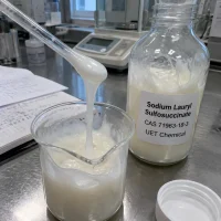 sodium-lauryl-sulfosuccinate-cas-71963-18-3-white-creamy-paste-sample White creamy Sodium Lauryl Sulfosuccinate (CAS 71963-18-3) mild surfactant paste poured into a beaker beside a UET Chemical bottle