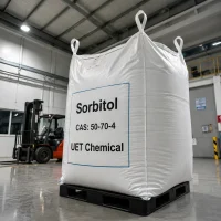 sorbitol-cas-50-70-4-1000kg-white-ton-bag-bulk-packaging Large white jumbo bag (ton bag) of Sorbitol CAS 50-70-4 on a black plastic pallet in a warehouse, label showing UET Chemical branding, with a forklift visible in the background.