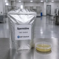 spermidine-cas-124-20-9-silver-foil-bag-sample A silver foil bag of Spermidine CAS 124-20-9 labeled UET Chemical, with a sample dish of pale yellow liquid beside it, on a stainless steel table in a clean lab environment.