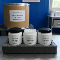 succinic-anhydride-packaging-options-1kg-bottle-25kg-drum Three white plastic bottles (Net 1 kg each) and one large cardboard drum (Net 25 kg) of Succinic Anhydride (CAS 108-30-5) arranged on foam tray, all labeled UET Chemical, showcasing multiple packaging sizes for lab and industrial use