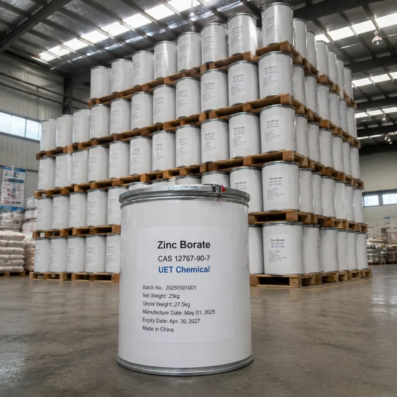 zinc-borate-cas-12767-90-7-25kg-white-metal-drum-pallet-warehouse A 25kg white metal drum of Zinc Borate CAS 12767-90-7 on a wooden pallet, labeled with batch number and manufacture date by UET Chemical, with rows of drums in the warehouse background.